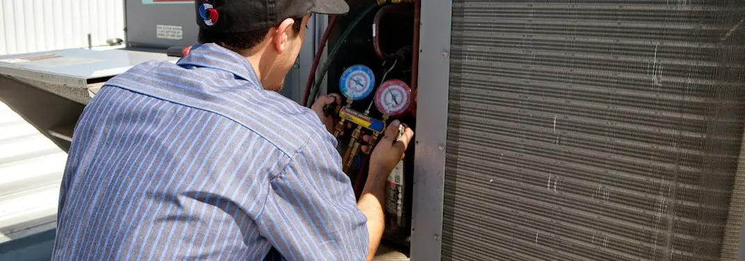 HVAC technician servicing a condenser unit in Johnston